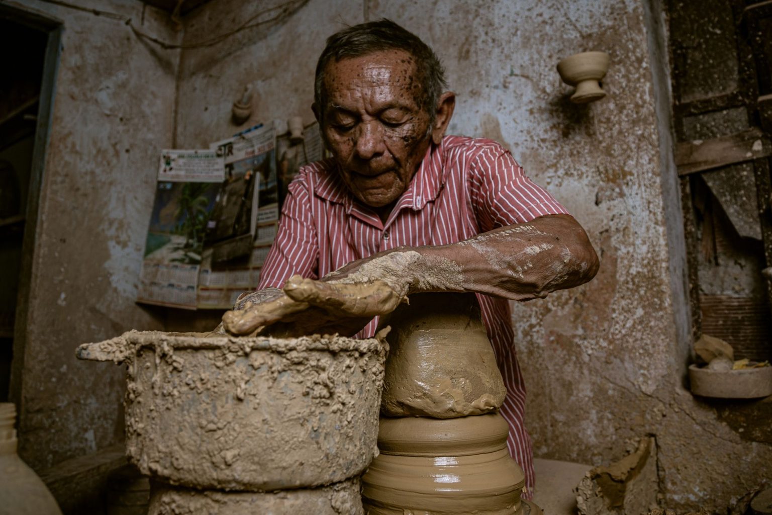 Artesão idoso produzindo uma peça de cerâmica artesanal em uma oficina.