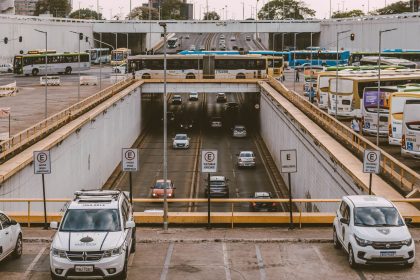 Ônibus e carros circulam por um viaduto em um movimentado cruzamento urbano.