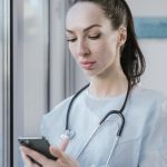 Médica usando um smartphone em um ambiente hospitalar.