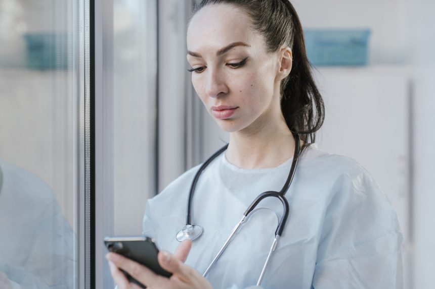 Médica usando um smartphone em um ambiente hospitalar.